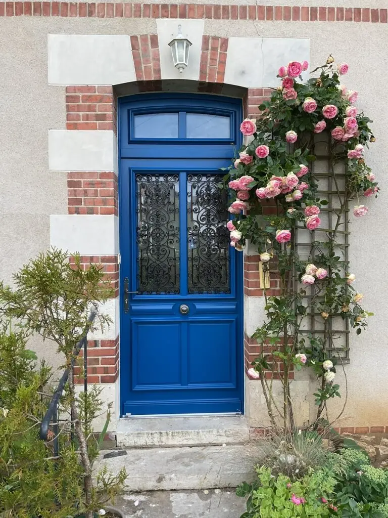 Magnifique porte d'entrée bleue avec des ferronneries en partie haute